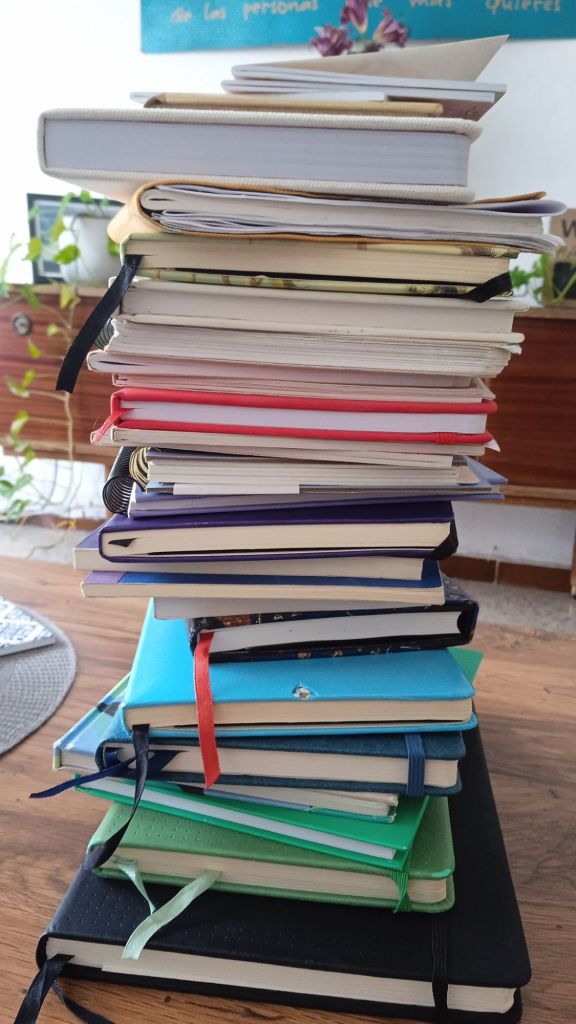 A pile of colourful notebooks piled high on a coffee table